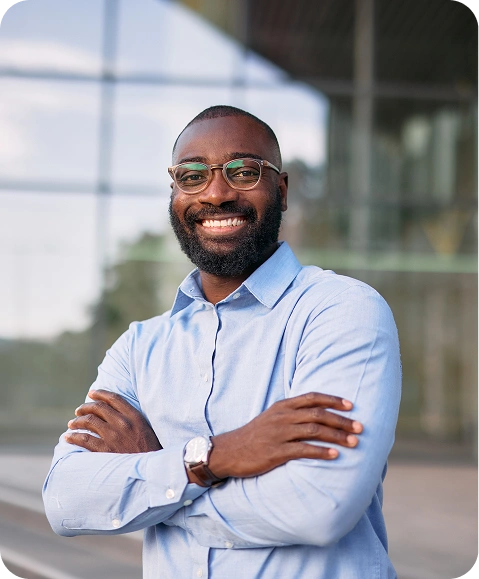 man in blue button down shirt & glasses smiling at the camera