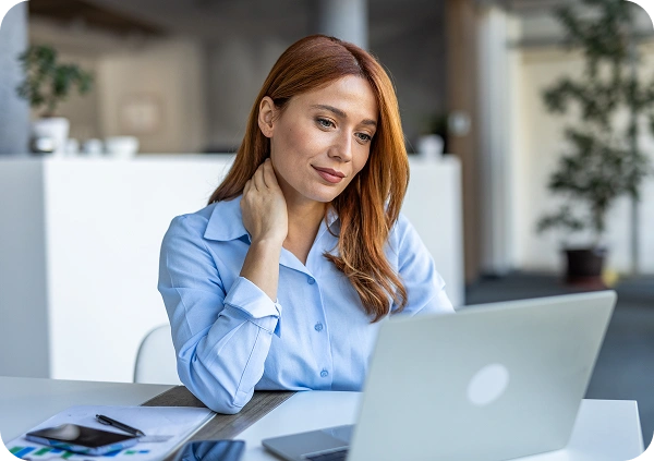 redhead businesswoman sitting at her desk in-office looking at her laptop